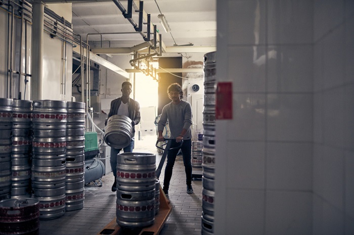 Mitarbeiter einer Brauerei verladen Bier mit Hubwagen