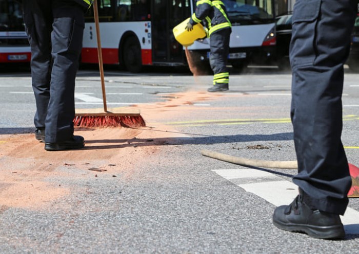 drei-menschen-entfernen-oelflecken-vom-asphalt