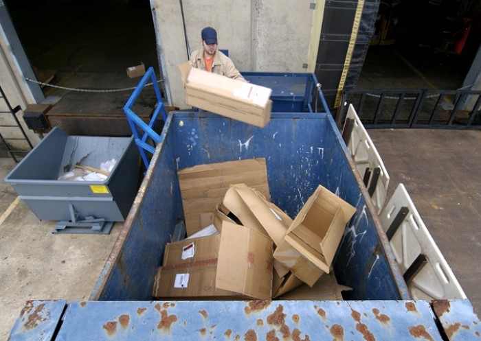 Person entsorgt Müll in einem Container