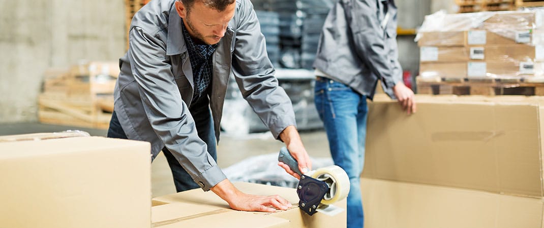 Zwei Männer mit Arbeitsmitteln im Lager