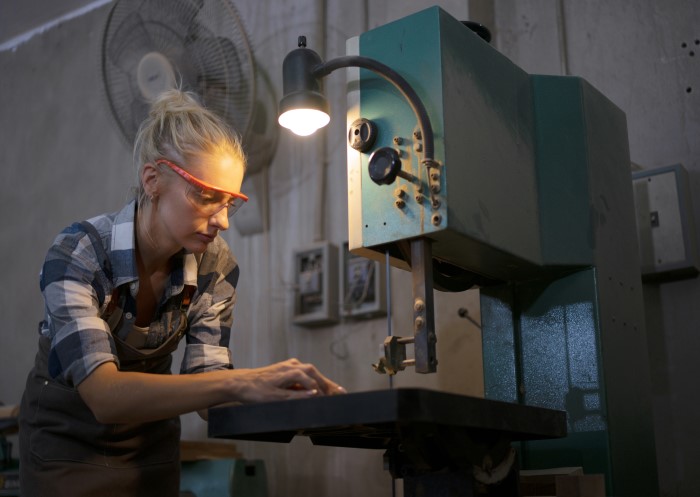 Tischlerin arbeitet in einer beleuchteten Werkstatt