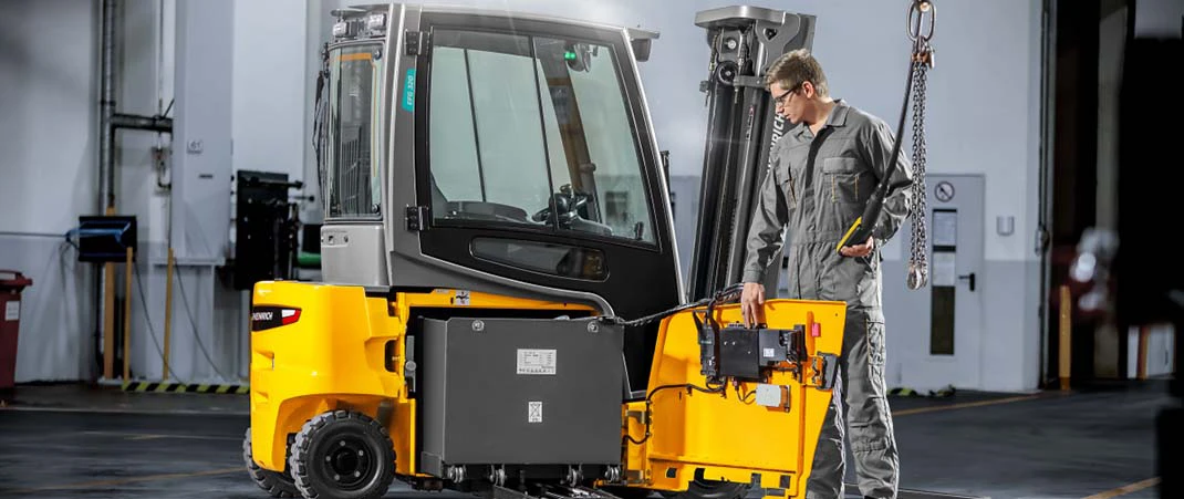 Ein Mann entfernt den Akku eines Gabelstaplers im Sinne der Prüfpflicht