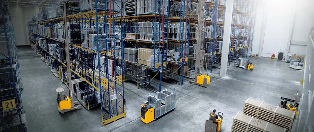 Hubwagen und Hochhubwagen unterschiedlicher Maße fahren durch ein Hochregallager