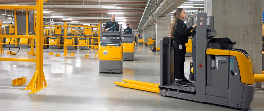 Flurförderzeug Lexikon: Mitarbeiter bedienen Gabelstapler und Hubwagen in einem großen Warenlager